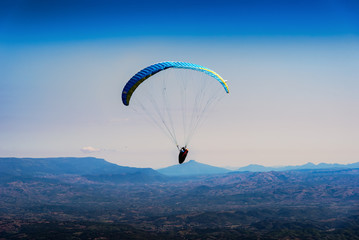 Paraglider flying over mountains in the morning on summer day at north of Thailand.