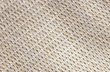 Background texture of beige pattern. Knitted fabric made of cotton or wool. Close-up, selective focus, top view, copy space.