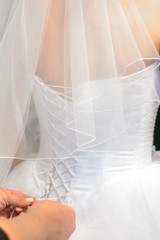Corset wedding dress being tied by mother's hands