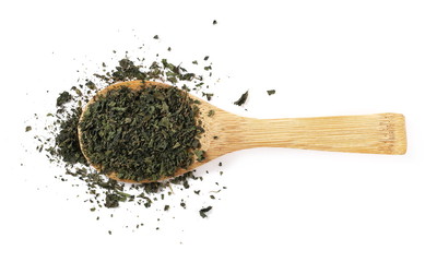Dry, cut and sliced nettle pile in wooden spoon, isolated on white background, top view