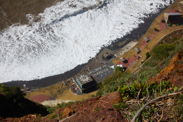 View of the coastline of Caniço, Madeira and a building with Welcome to Paradise written on the top