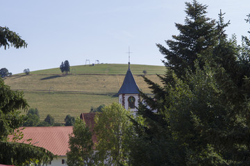 View over roofs past the church tower in Gernsbach to a ski lift in summer