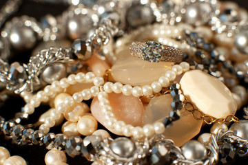 Jewelry in a pile. Macro. Many jewelry shines on a black background. Bijouterie is a kind of accessories for women's fashion.