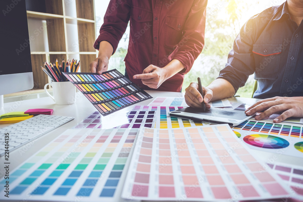 Poster Two colleagues creative graphic designer working on color selection and drawing on graphics tablet at workplace
