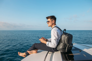 sailing, tourism, travel, business and people concept - handsome man on sail boat or yacht floating...