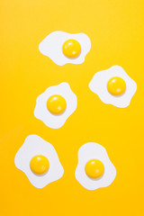 paper fried egg, set against a backdrop of yellow paper. Horizontal view over