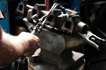 The welder's hand repairing metal parts with gas welding