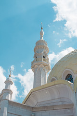 The tall, white tower of the mosque against the blue sky.