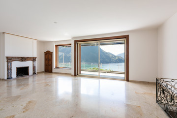 Empty living room with large windows overlooking the lake.