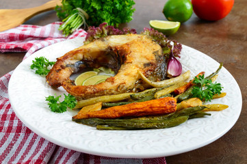 Fried fish steak with grilled vegetables on a white plate. Proper nutrition.