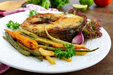 Fried fish steak with grilled vegetables on a white plate. Proper nutrition.