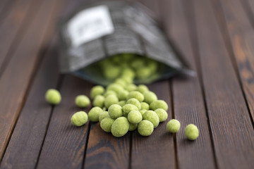 Peanuts with wasabi on wooden background, snack. Close up.