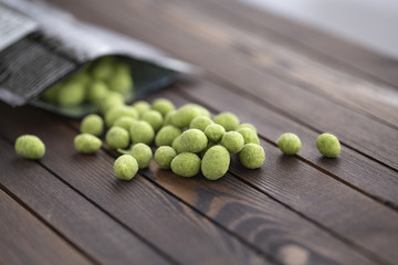 Peanuts with wasabi on wooden background, snack. Close up.
