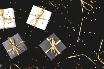 Obraz na płótnie Canvas Black and white gift boxes with gold ribbon on shine background.