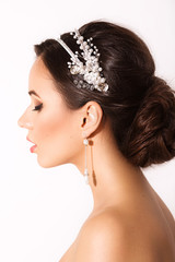 Portrait of beautiful young brunette woman with makeup and by a beautiful hair-do by the decorated stylish bijouterie 