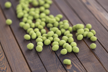 Peanuts with wasabi on wooden background, snack. Close up.