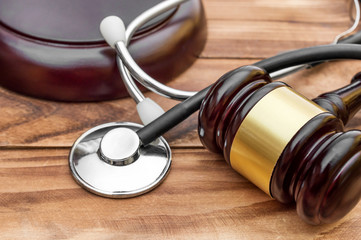 Gavel with stethoscope on wooden table. Medical law. Close up.