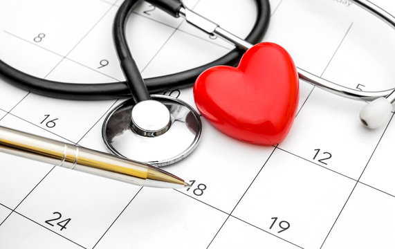 Pen Pointing On Calendar With Stethoscope And Red Heart. Date For Medical Examiner.