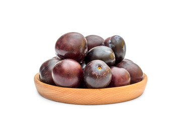 Obraz premium Wooden bowl with ripe plums on white. Top view.