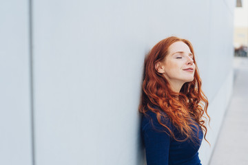 Smiling relaxed woman standing with closed eyes