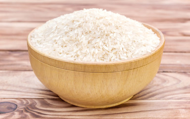 Wooden bowl with rice on wooden background.