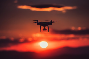 Flying drone against sunrise cloudscape