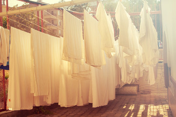 Drying clothes in the unusual sunset. White towels and sheets dry in the sun near the hotel. Washing laundry from the laundry is dried in the sun on the clothesline.