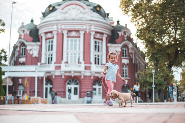 Obraz premium Little kid walking her cocker spaniel outdoors on the city center Varna, Bulgaria summer vacation
