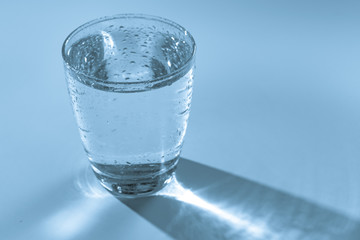 Glass with water on blue background