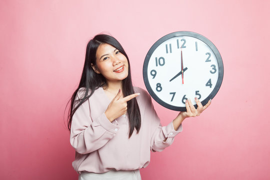 Young Asian woman point to a clock.
