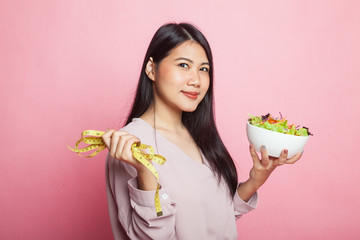 Healthy  Asian woman with measuring tape and salad.