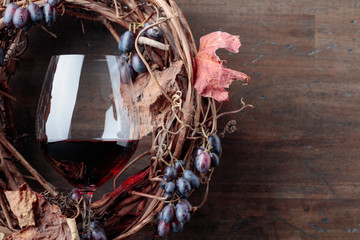 Glass of red wine with grapes and dried vine leaves.