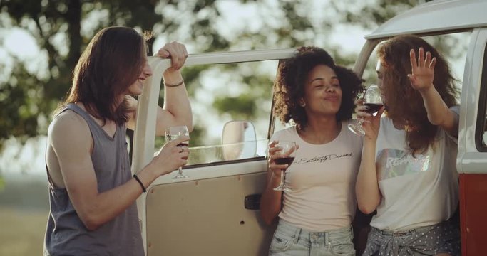 Stylish three friends from 90 s have a good time together , at the nature drinking wine. 4k. slow motions
