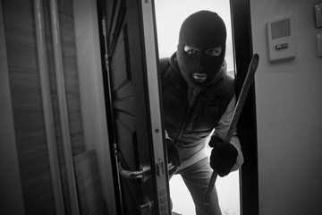 Burglar breaking in a house with crowbar