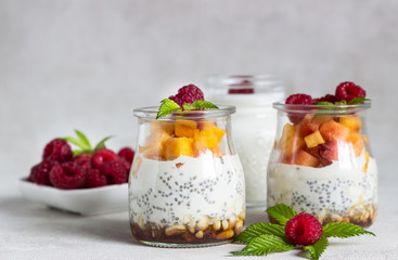 Vanilla chia seeds pudding in glasses with fresh raspberries and peaches. Healthy dessert breakfast.