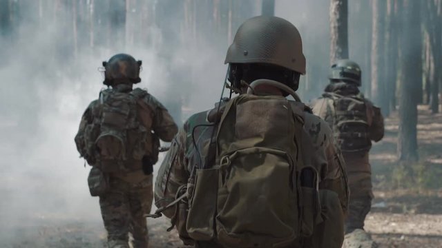 US Army soldiers run through the smoggy forest during battle