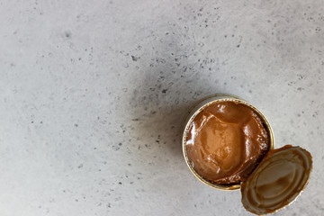 Dulce de leche in a metal tin on a natural stone background.