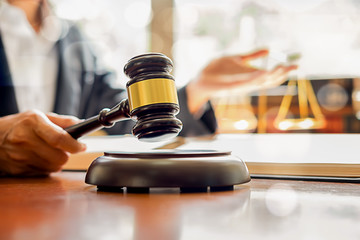 Judge gavel with Justice lawyers having team meeting at law firm background. Concepts of Law and Legal services.