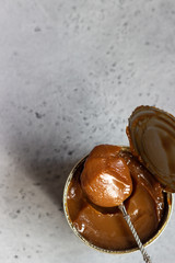 Dulce de leche in a metal tin on a natural stone background.