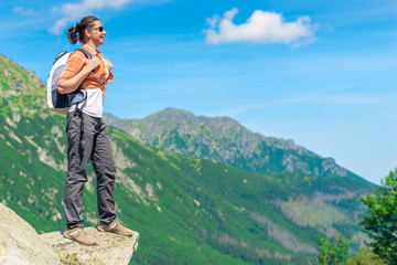 Naklejka premium horizontal portrait of a happy tourist with a backpack on a background of high mountains