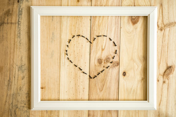 Viejo marco blanco vintage con herramientas variadas con forma de corazón sobre fondo de madera