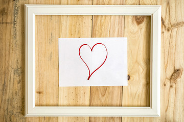 Viejo marco blanco vintage con dibujos de amor y corazón sobre papel sobre fondo de madera