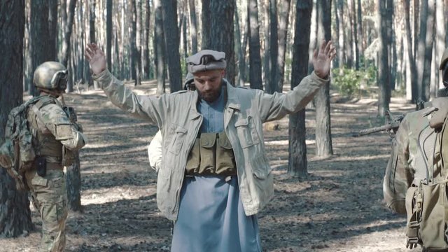 Slow motion of soldiers capturing Mujahideen man in forest