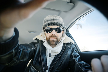 driver of the car in winter clothes, man behind the wheel, a winter journey on car,  brutal man...