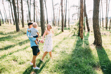 Naklejka na ściany i meble A cute family - mom, dad and son spend fun time in nature