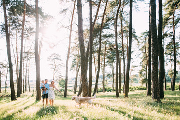 Fototapeta premium A cute family - mom, dad and son spend fun time outdoors with their dog
