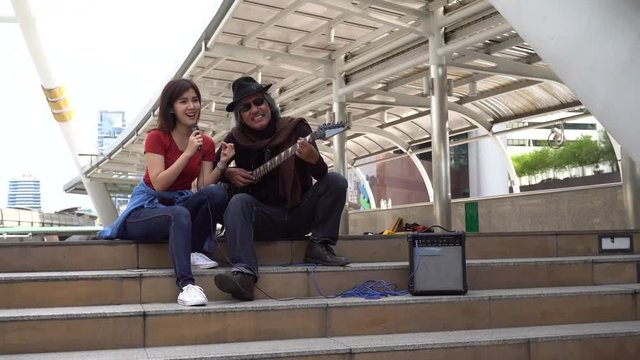 Street musician duo of female singer and male guitarist performing on the street