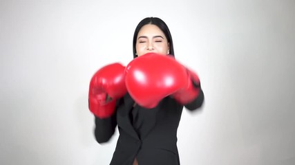 Young happy and energetic business woman keeps punching and raising hands with boxing gloves on white background - Powered by Adobe