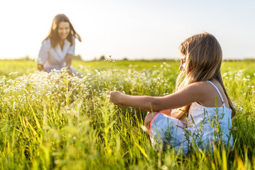 mother and daughter spending time together in green meadow on sunset