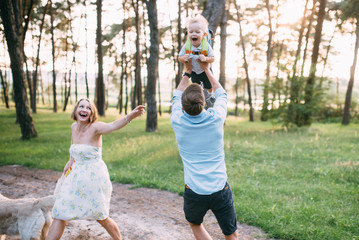 Obraz premium A cute family - mom, dad and son spend fun time outdoors with their dog